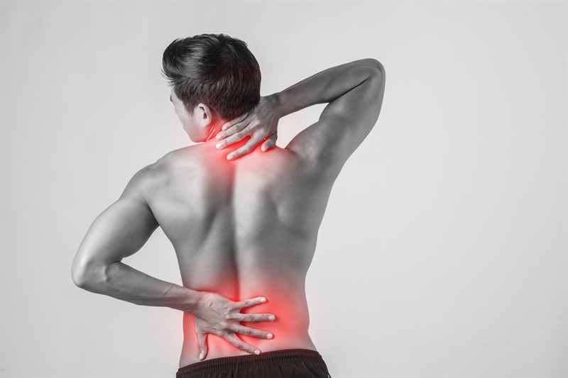 ein Mann fasst sich an den Nacken und den unteren Rücken, um die Rückenschmerzen zu lokalisieren